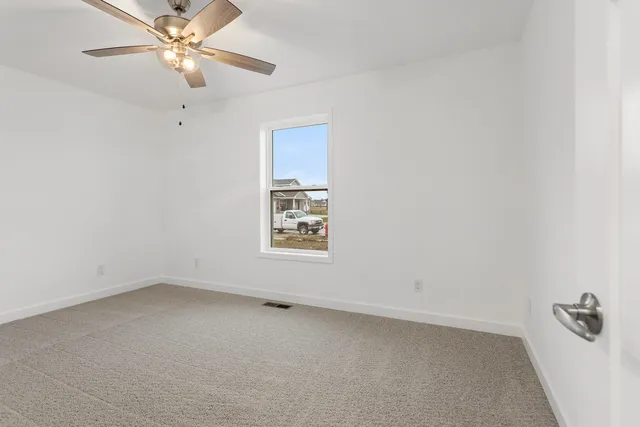 an empty room with a window and a fan