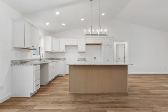 a kitchen with kitchen island granite countertop a sink cabinets and wooden floor