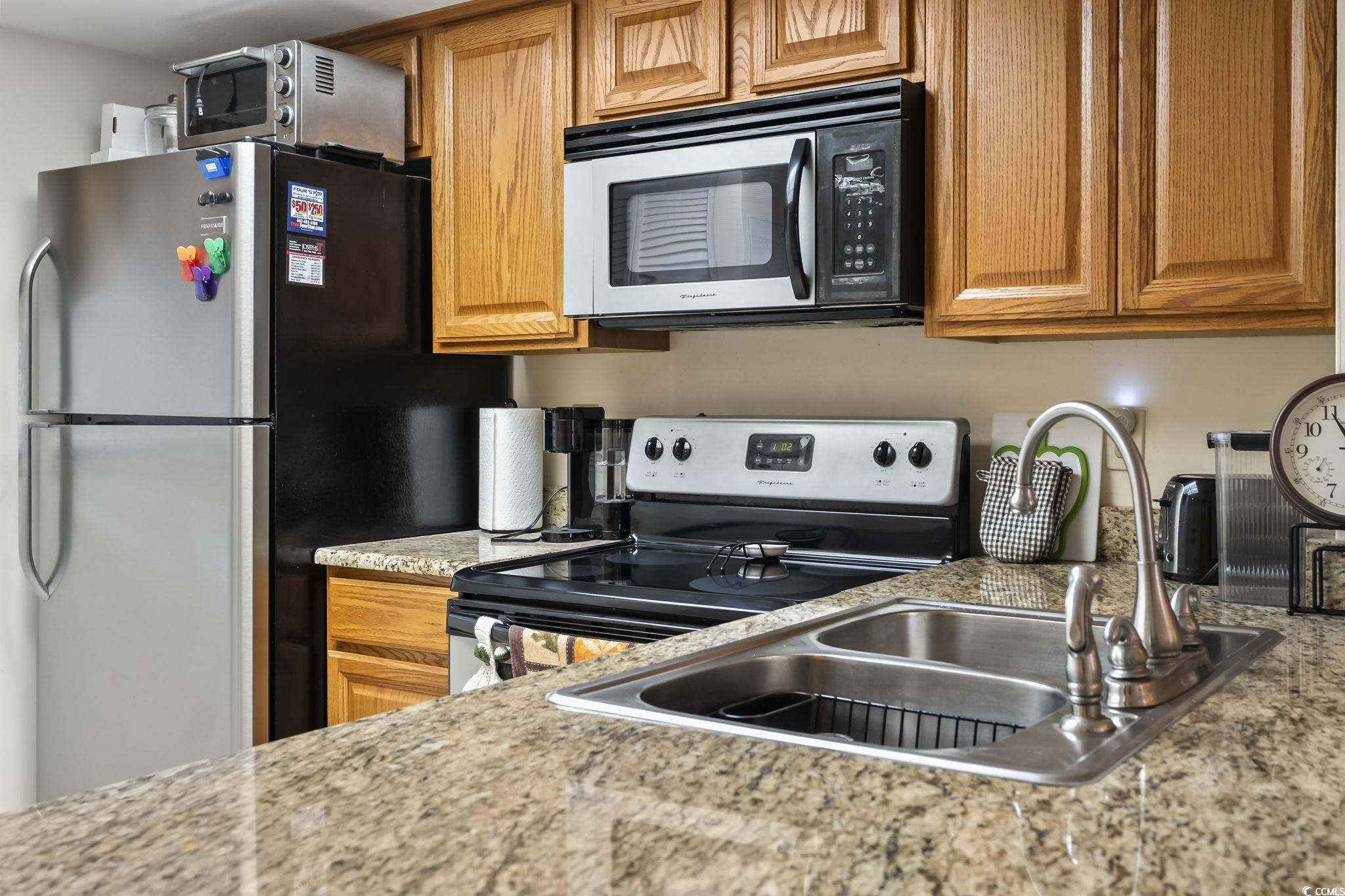 1301 Pridgen Road, Unit 304 Myrtle Beach, SC 29577 - Photo 6 of 26 Kitchen featuring a peninsula, stainless steel appliances, light tile patterned flooring, and brown cabinets