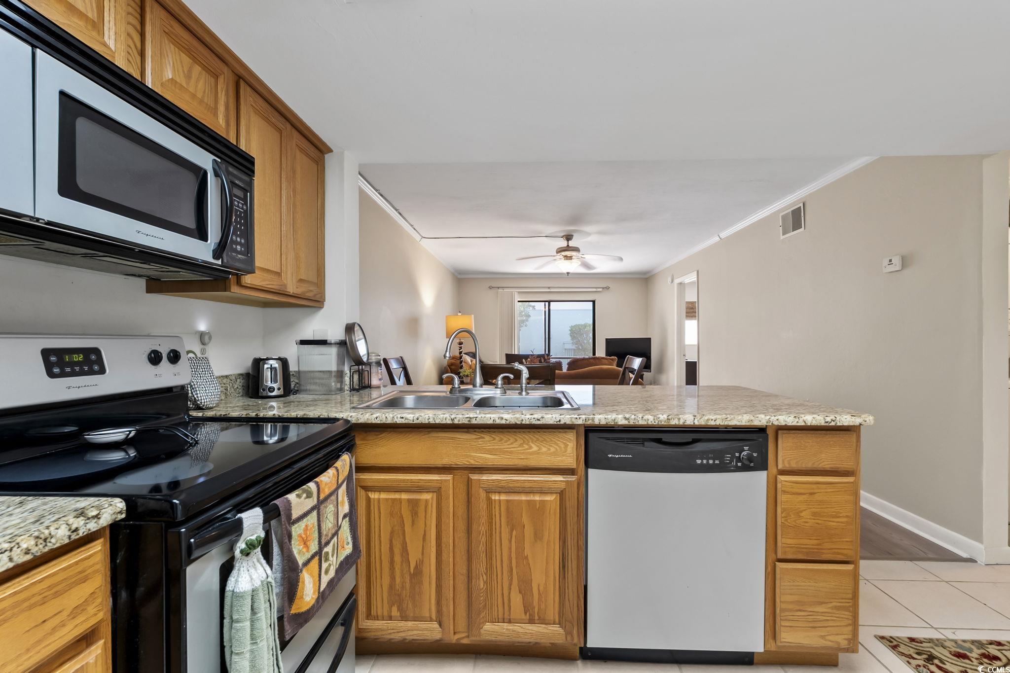 1301 Pridgen Road, Unit 304 Myrtle Beach, SC 29577 - Photo 8 of 26 Kitchen featuring appliances with stainless steel finishes, brown cabinets, light tile patterned floors, a peninsula, and a skylight