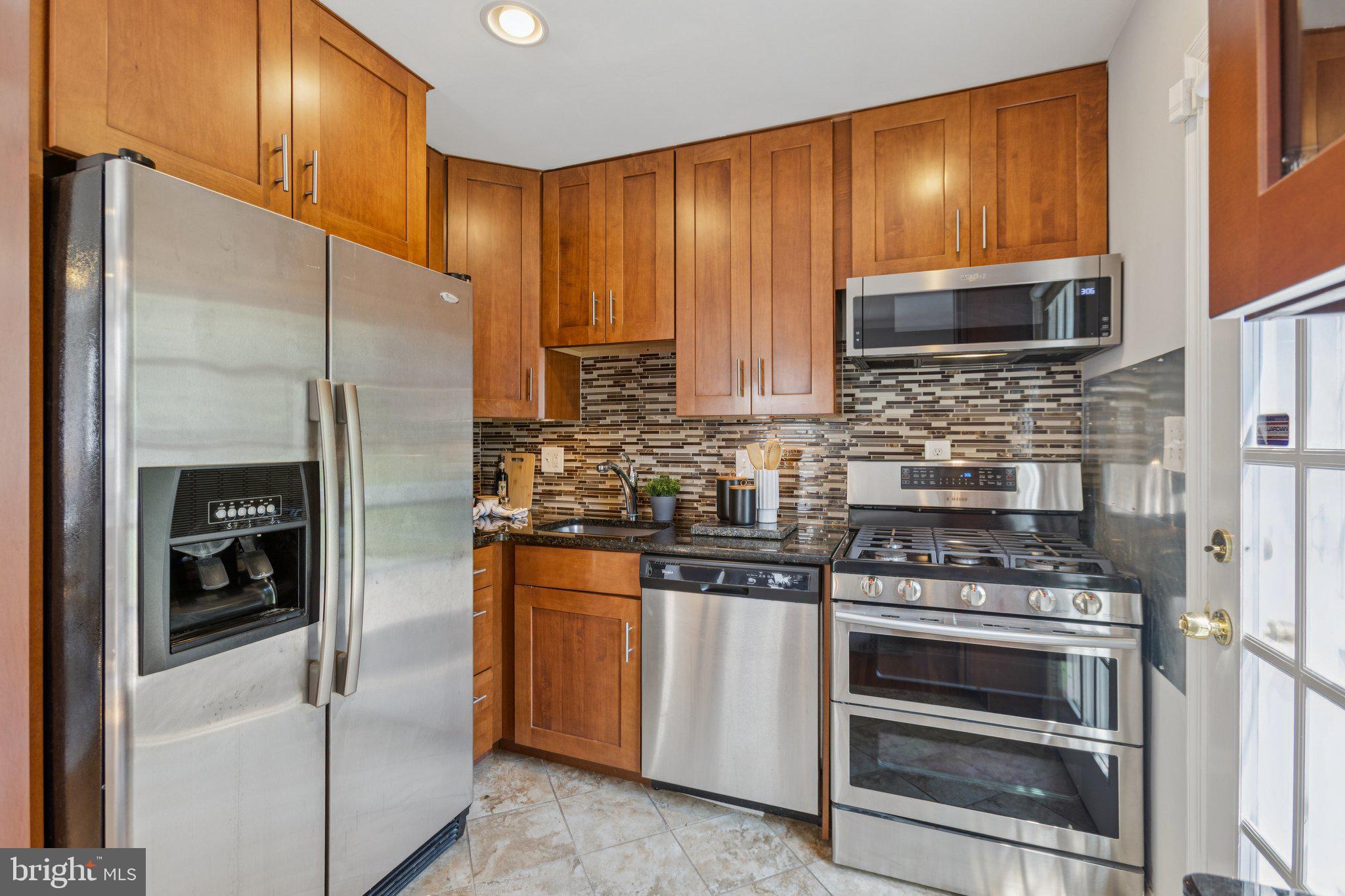 1718 Dublin Drive Silver Spring, MD 20902 - Photo 7 of 25 a kitchen with stainless steel appliances granite countertop a stove and a refrigerator