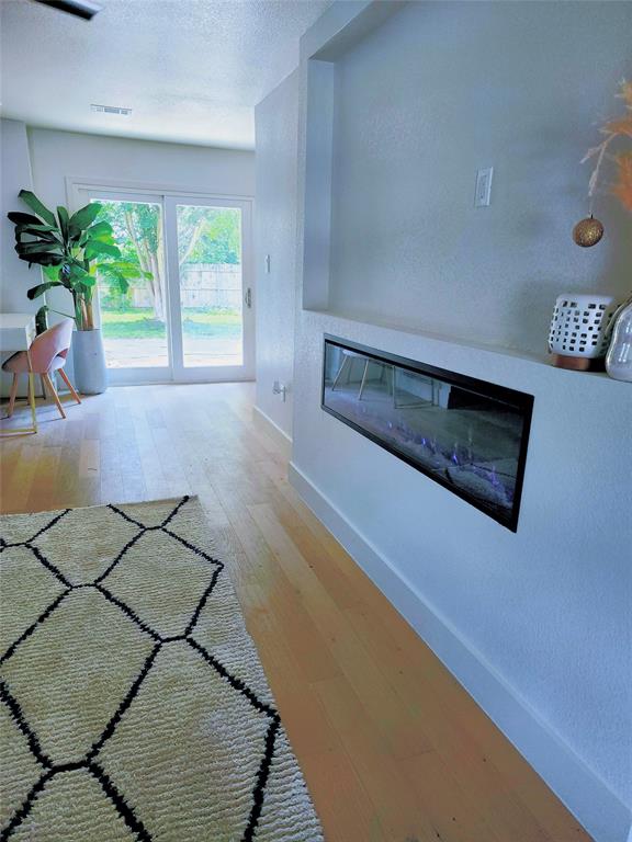2908 Washington Street Commerce, TX 75428 - Photo 16 of 29 Integrated linear fireplace with a built-in mantel, light wood-finish flooring, and white baseboards
