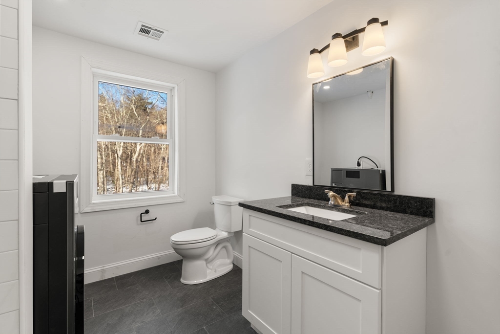 99 Main Street, Unit A Upton, MA 01568 - Photo 16 of 21 a bathroom with a granite countertop sink toilet and mirror