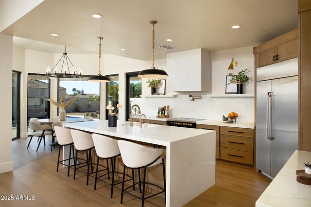 a kitchen with a sink a refrigerator and chairs