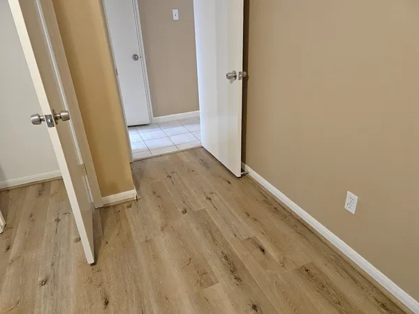 a view of an empty room with wooden floor and a window