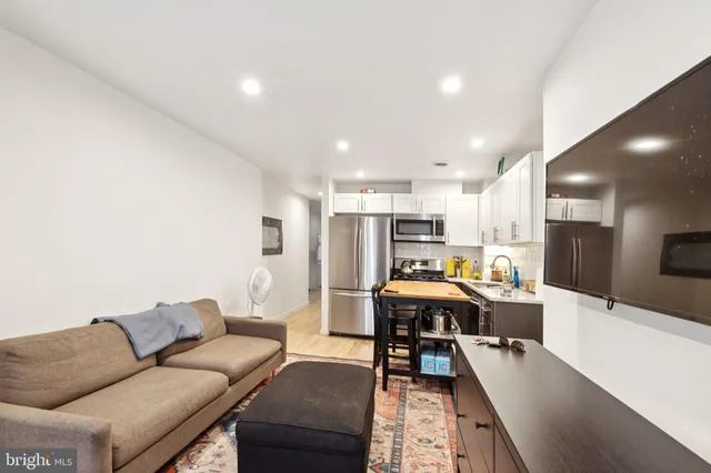 a living room with stainless steel appliances kitchen island dining table and a couch