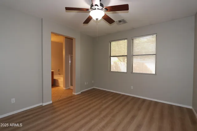 a view of empty room with wooden floor and fan