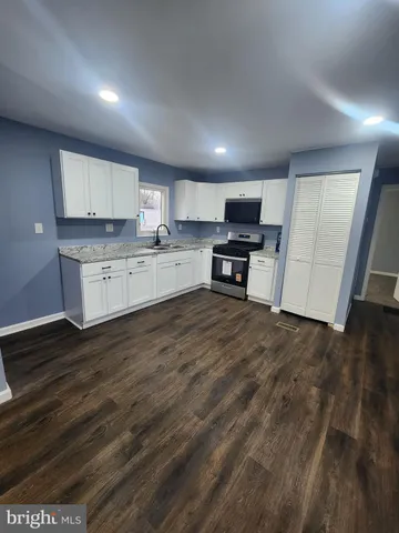 a kitchen with granite countertop a sink cabinets and wooden floor
