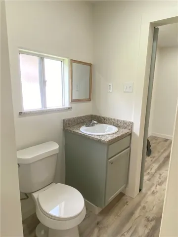 a bathroom with a granite countertop toilet a sink and a mirror