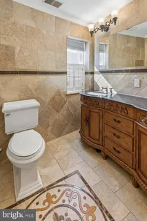 a bathroom with a granite countertop toilet sink and mirror