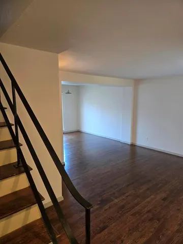 a view of an empty room with wooden floor and stairs