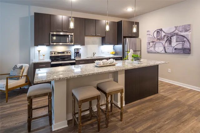 a kitchen with stainless steel appliances granite countertop a table chairs sink and cabinets