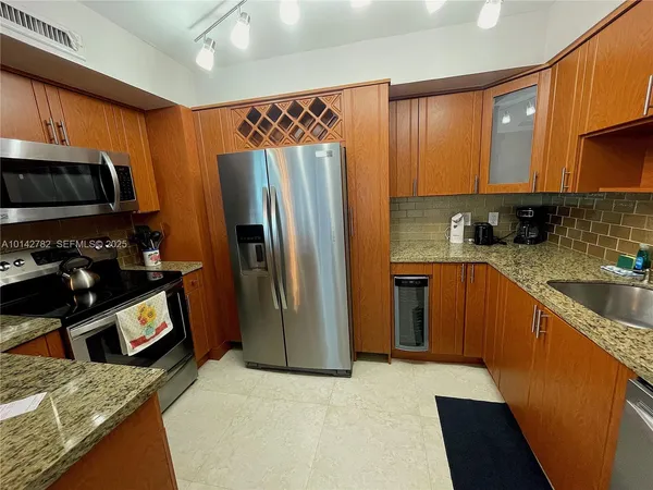 a kitchen with stainless steel appliances granite countertop a refrigerator a stove a sink and dishwasher