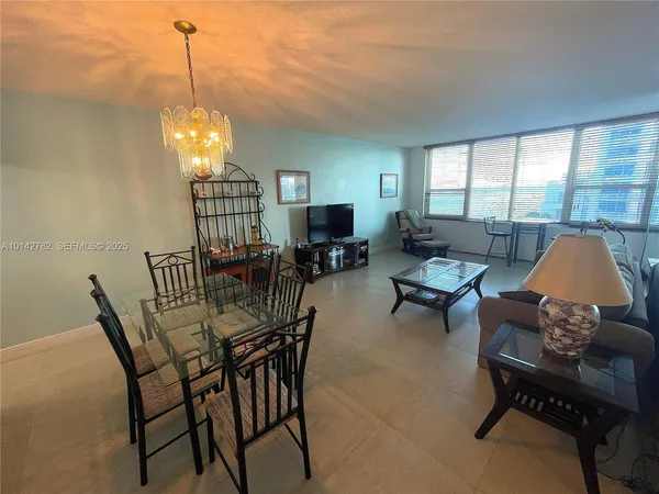 a view of a livingroom and dining room with furniture wooden floor a rug and a chandelier