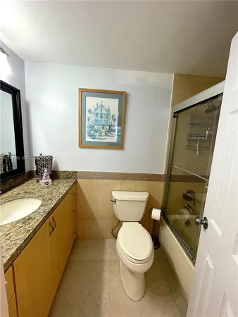a bathroom with a granite countertop toilet sink and mirror