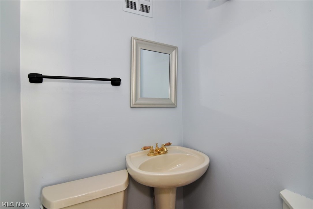 5284 Edenhurst Road Lyndhurst, OH 44124 - Photo 31 of 50 Pedestal sink with brass-finish faucet, framed mirror, and matte black towel bar