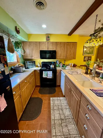 a large kitchen with stainless steel appliances granite countertop a stove a sink dishwasher and a microwave