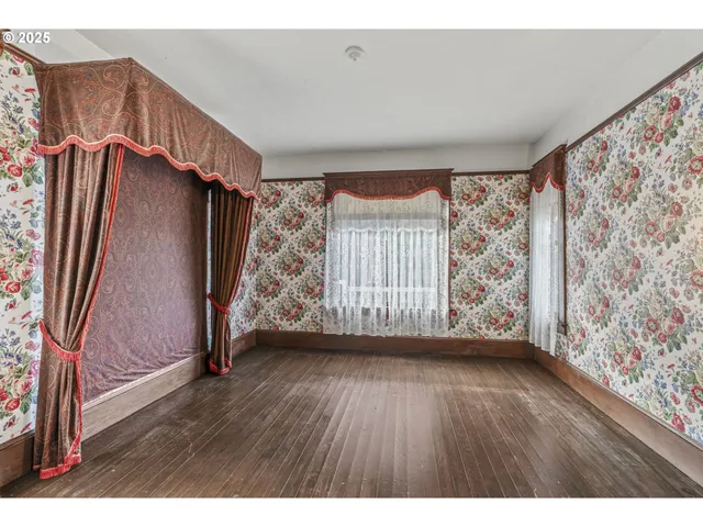 a view of an empty room with wooden floor closet and fire place