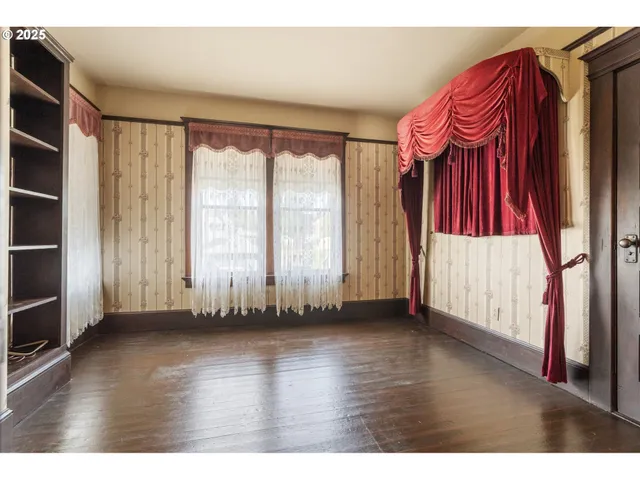 a view of an empty room with wooden floor and stairs