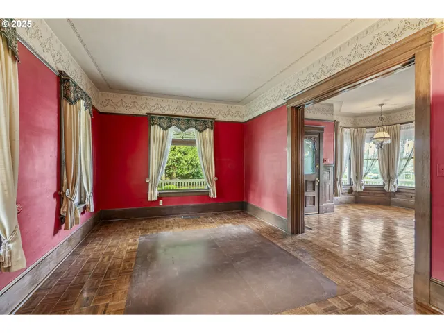 a view of empty room with floor to ceiling window and wooden floor