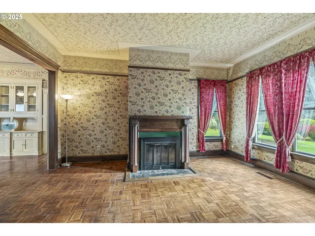 a view of an empty room with wooden floor and a fireplace