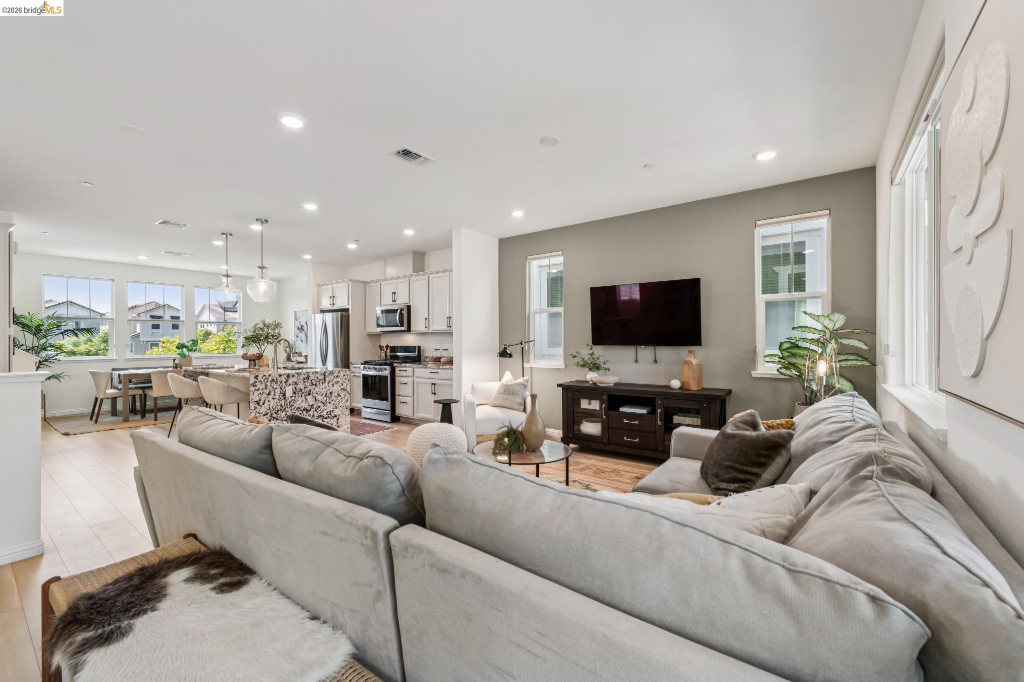 24157 Amaranth Loop Hayward, CA 94541 - Photo 16 of 63 Open-concept living space featuring wood-finish flooring, recessed lighting, a modern kitchen with stainless steel appliances, a dining area with multiple windows, and a kitchen island with pendant lighting