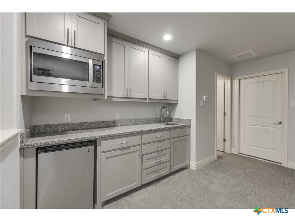 1729 Las Lomas Court Temple, TX 76502 - Photo 28 of 43 Granite-topped bar with sink, microwave, and mini-fridge