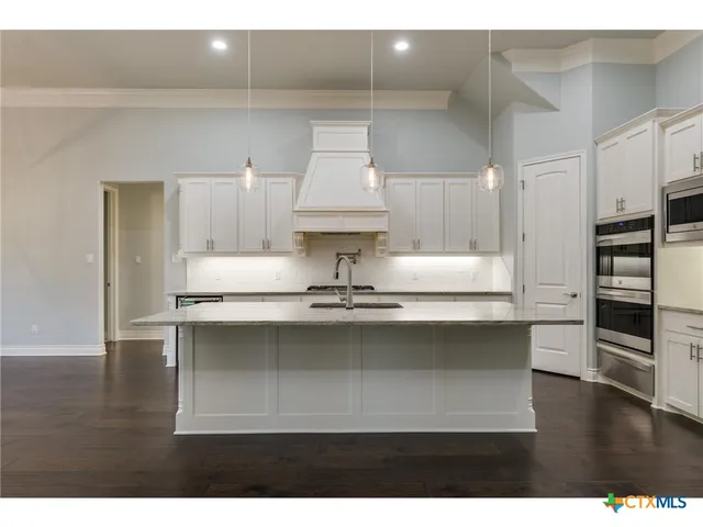 a kitchen with stainless steel appliances granite countertop a stove refrigerator and cabinets