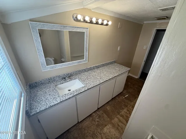 a bathroom with a granite countertop sink and a mirror