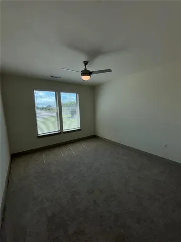 an empty room with windows and ceiling fan