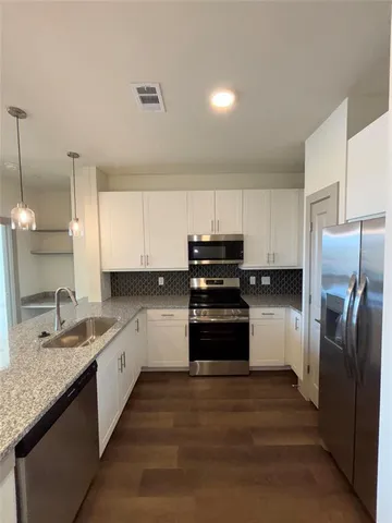 a kitchen with stainless steel appliances granite countertop a refrigerator a stove and a sink