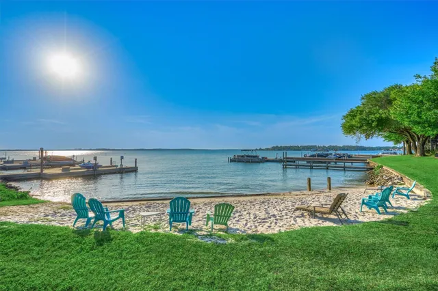 a view of a lake with lawn chairs and a large tree