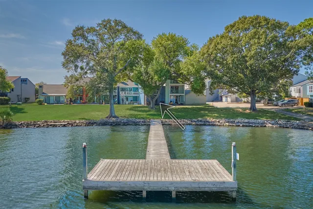a wooden bench sitting in middle of a lake next to a yard