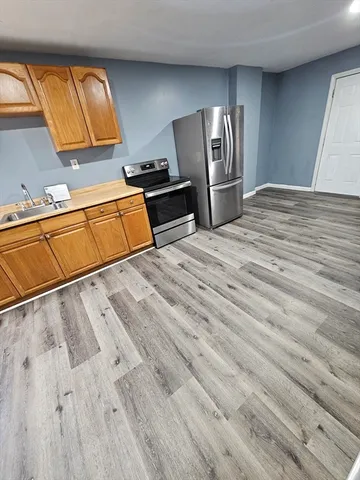 a view of kitchen and empty room with wooden floor