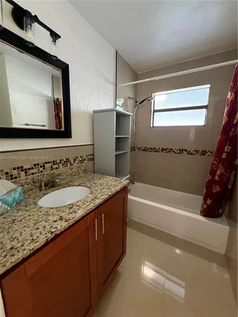 a bathroom with a granite countertop sink a mirror and a bathtub