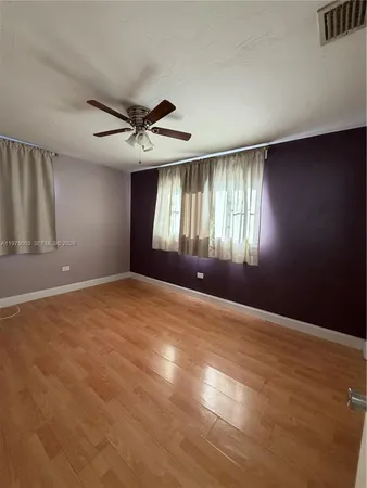 an empty room with windows and ceiling fan view