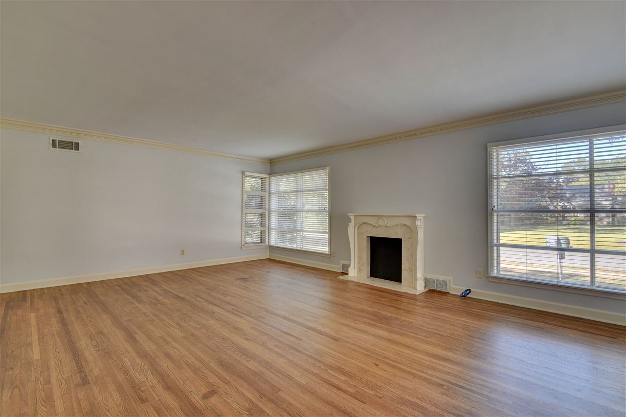 4053 Minden Road Memphis, TN 38117 - Photo 3 of 22 an empty room with wooden floor fireplace and windows