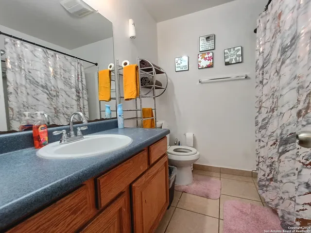 a bathroom with a granite countertop sink a toilet and a shower curtain