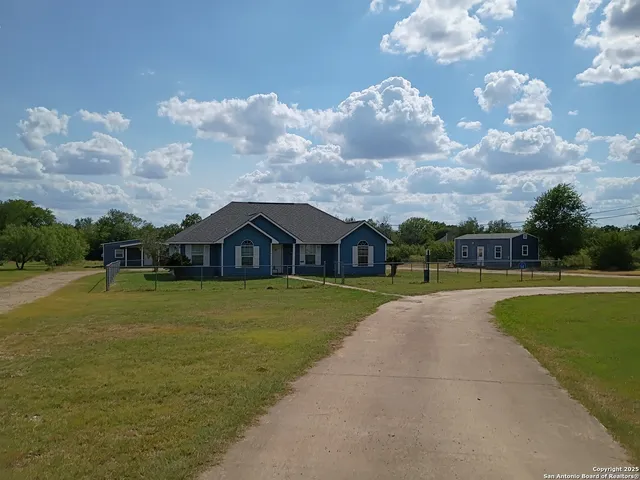 a view of a house next to a yard with plants and large trees