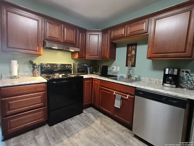 a kitchen with granite countertop wooden cabinets and a stove top oven
