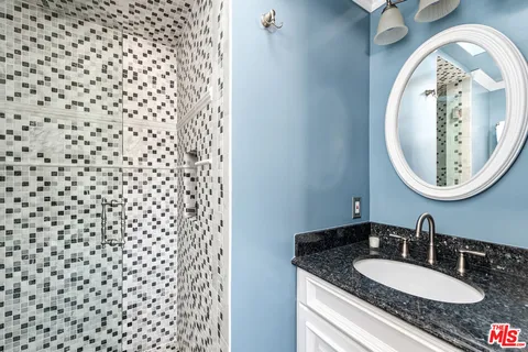 a bathroom with a granite countertop sink and a mirror