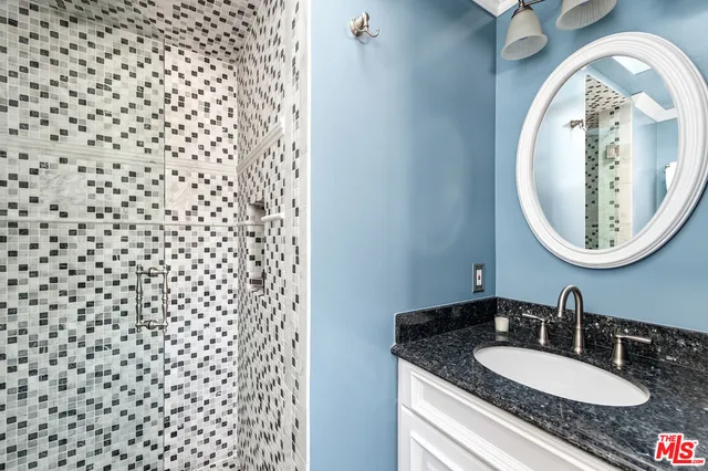 a bathroom with a granite countertop sink and a mirror