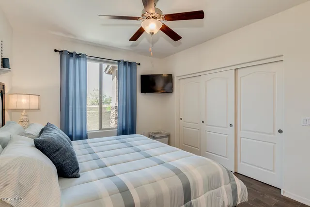 a bedroom with a bed and a flat tv screen on the dresser