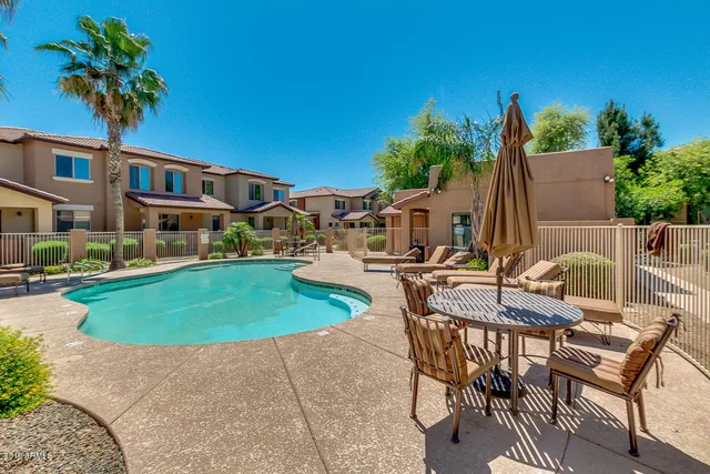 a view of pool with lawn chairs under an umbrella