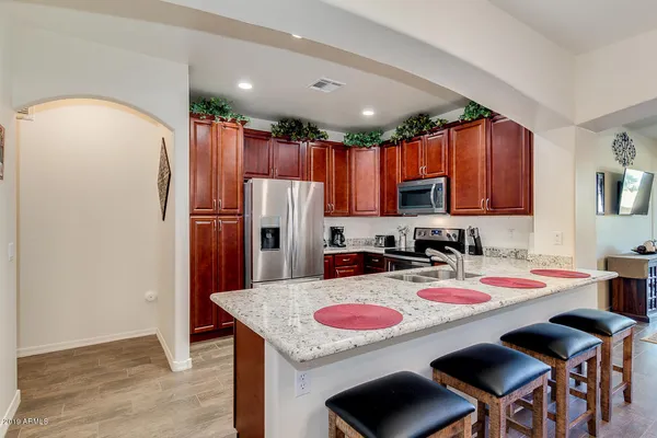 a kitchen with stainless steel appliances granite countertop a stove a refrigerator a sink a dining table and chairs