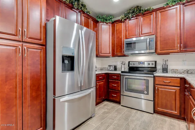 a kitchen with stainless steel appliances granite countertop a refrigerator and a stove top oven