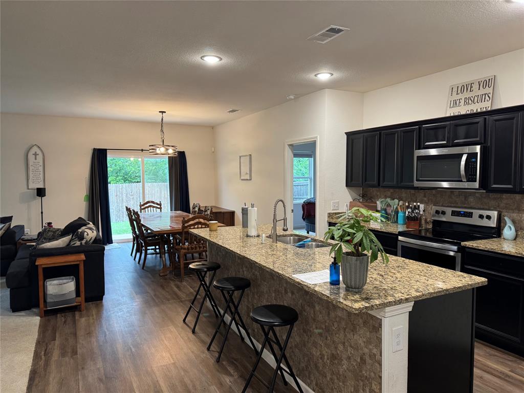 2209 Cinnamon Spgs Road Glenn Heights, TX 75154 - Photo 2 of 28 Open-concept kitchen and dining area featuring dark cabinetry, stainless steel appliances, and a granite-finish island with seating