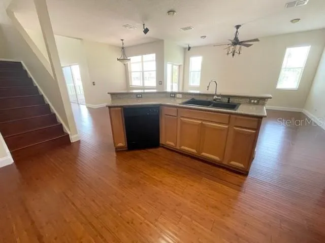 a view of a kitchen with kitchen island a sink wooden floor and a refrigerator