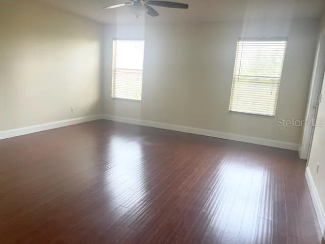 an empty room with wooden floor closet and windows