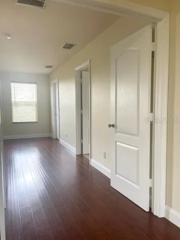 an empty room with wooden floor fan and windows